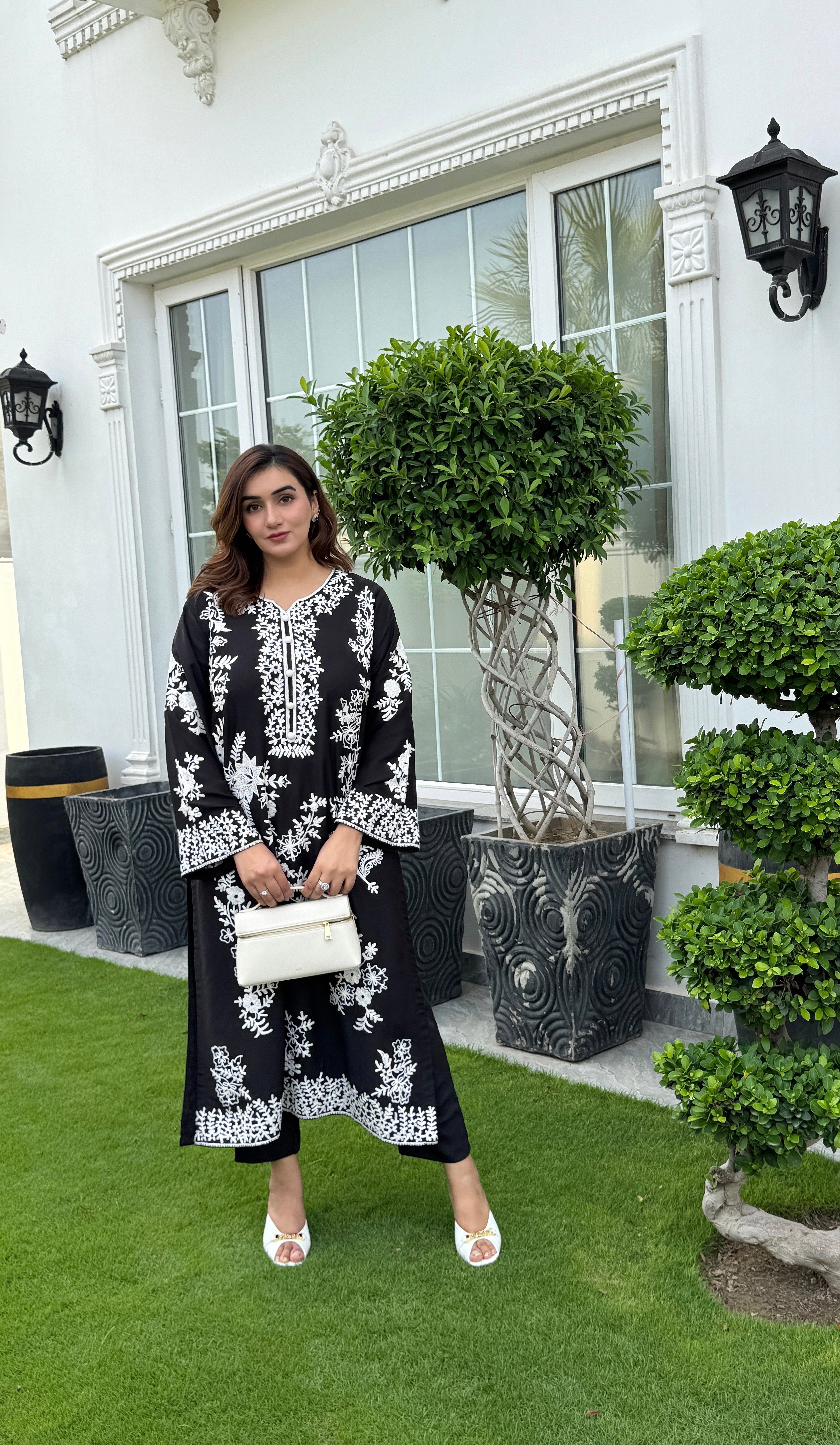 Model showcasing a hand-embroidered black georgette kurta with intricate white floral embroidery by Momina Ammar Clothing, a Pakistani kurta set style available with worldwide delivery to UK, UAE, USA, and Canada."