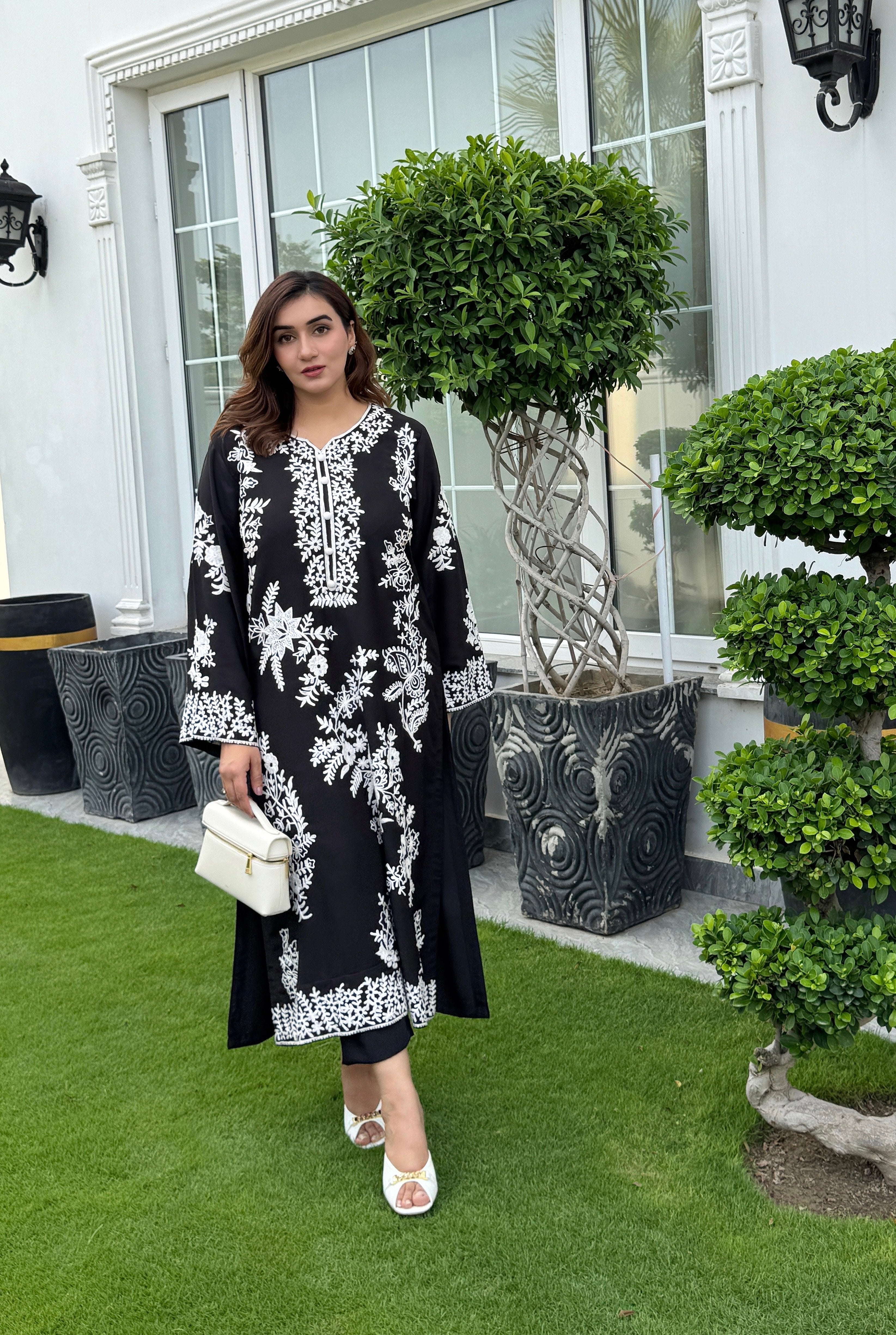 Model showcasing a hand-embroidered black georgette kurta with intricate white floral embroidery by Momina Ammar Clothing, a Pakistani kurta set style available with worldwide delivery to UK, UAE, USA, and Canada."