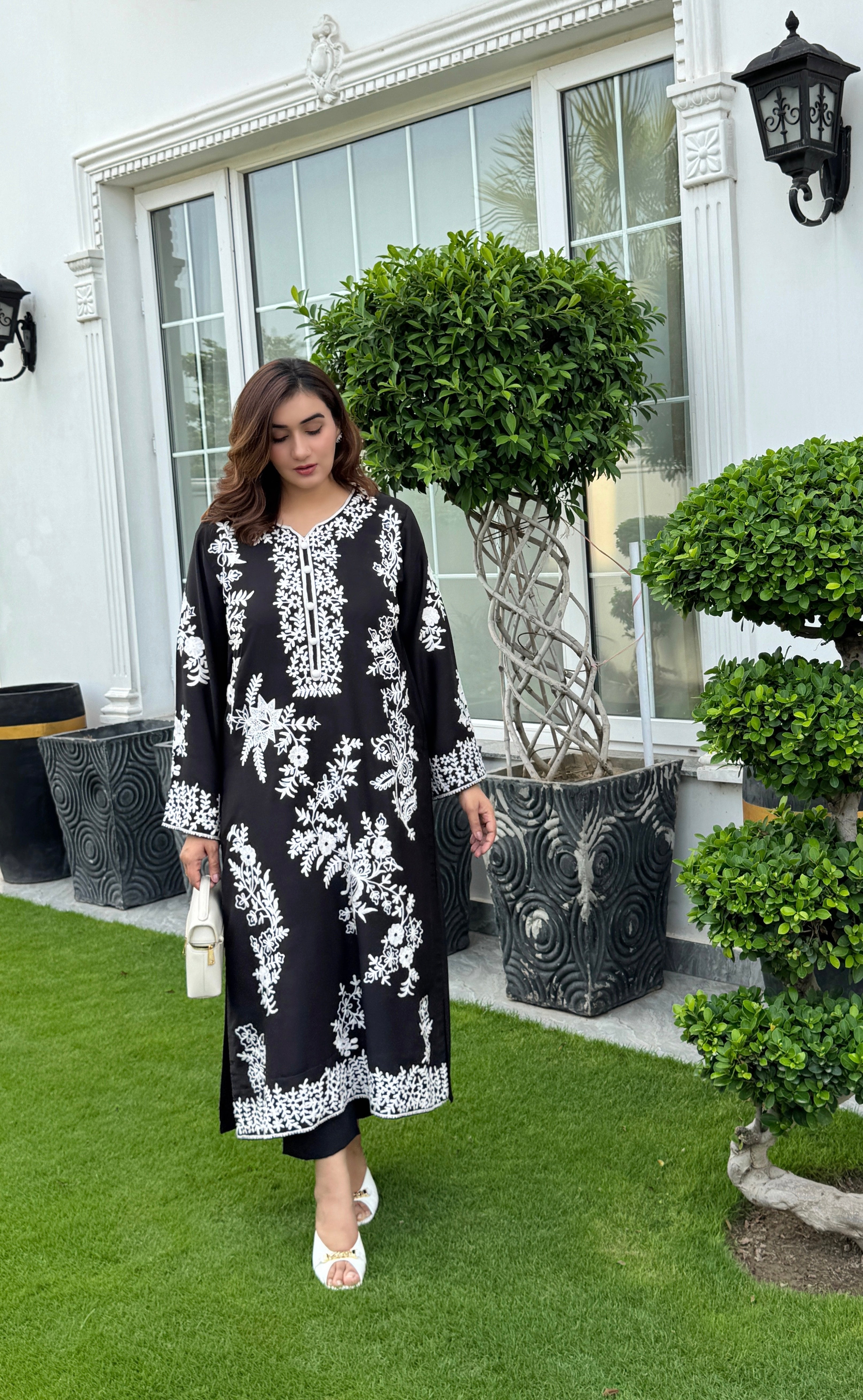 Model showcasing a hand-embroidered black georgette kurta with intricate white floral embroidery by Momina Ammar Clothing, a Pakistani kurta set style available with worldwide delivery to UK, UAE, USA, and Canada."